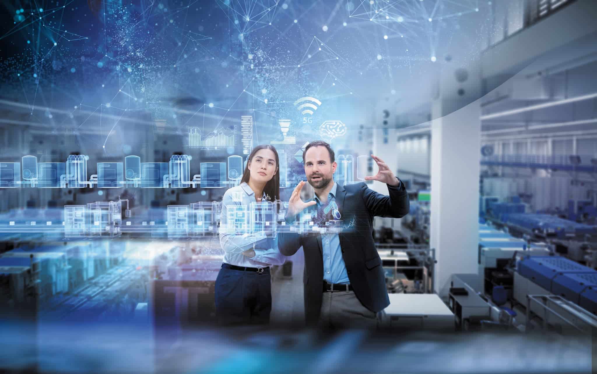 Deux personnes analysant une visualisation numérique de données dans un environnement industriel.